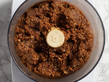 Figues, dattes et épices complètement mélangées dans le bol d’un robot culinaire