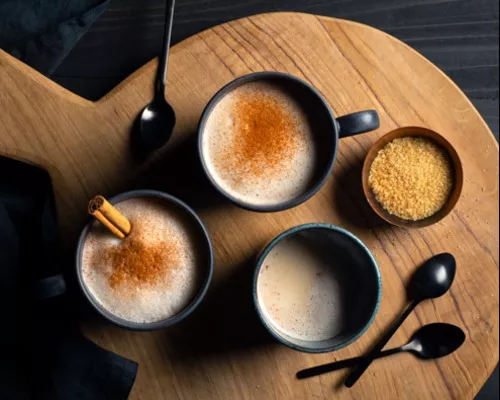 Trois tasses d’horchata chaude décorées de bâtons de cannelle et de cannelle en poudre