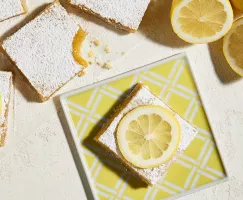 Barres de citron sur une assiette carré jaune avec des tranches de citron