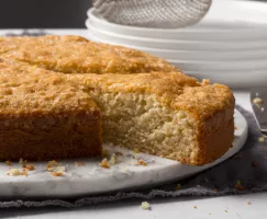 Gâteau pomme et brandy disposé sur une assiette de présentation en marbre avec une tranche découpée