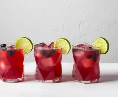 Trois verres de cocktail de bière aux bleuets garnis de bleuets et de lime