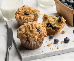 Trois muffins aux bleuets servis avec du lait et un panier de bleuets