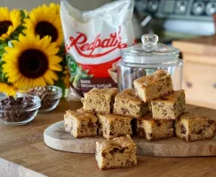 Blondies au beurre noisette avec pépites de chocolat disposés sur un comptoir de type bloc de boucher avec des tournesols