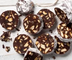 Tranches de salami au chocolat saupoudrées de sucre à glacer sur une planche à découper en bois