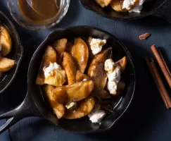 Une poêle en fonte pleine de poutine dessert incluant les tranches de pommes, la sauce au caramel et le fromage à la crème sucré
