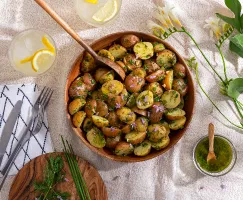 Salade de pommes de terre à l’aneth dans un bol en bois sur une nappe et un verre de limonade