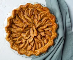 Une tarte hollandaise aux pommes sur une assiette avec un linge de cuisine