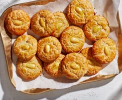 Une douzaine de biscuits dorés aux amandes sur un plateau en cuivre.