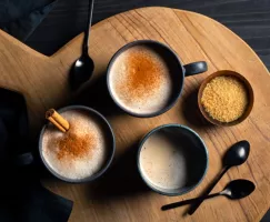 Trois tasses d’horchata chaude décorées de bâtons de cannelle et de cannelle en poudre