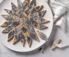 kaju katli sur une assiete coupé en losanges et décoré de feuilles d'argent