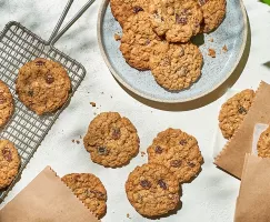 Biscuit moelleux avoine et raisins sur une assiette, une grille de refroidissement, une table et dans des enveloppes de papier