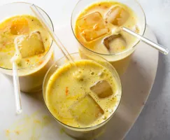Trois verres de latté au curcuma avec glaçons et pailles